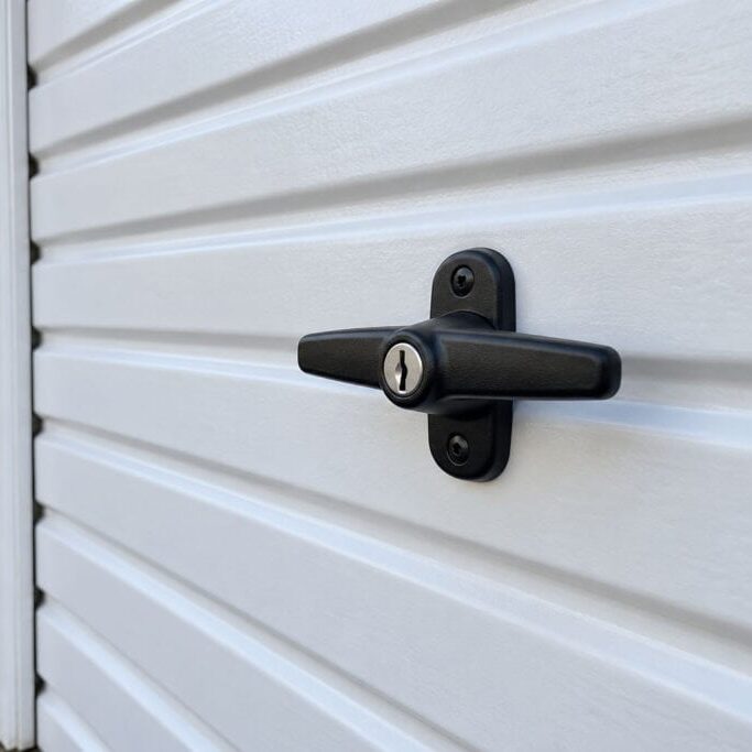 Black locking T-handle on a white ribbed garage door