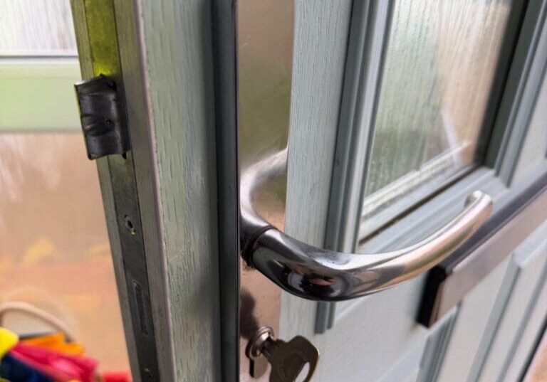Close-up image of a front composite door handle in silver finish with a key inserted in the keyhole at Greenhill Park, Bishop's Stortford.