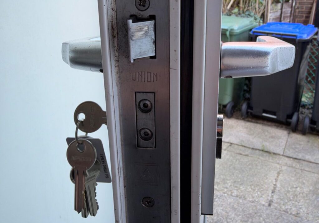 Close-up view of a locked metal multipoint door in Braintree showing the new euro profile cylinder with keys inserted and metal handle