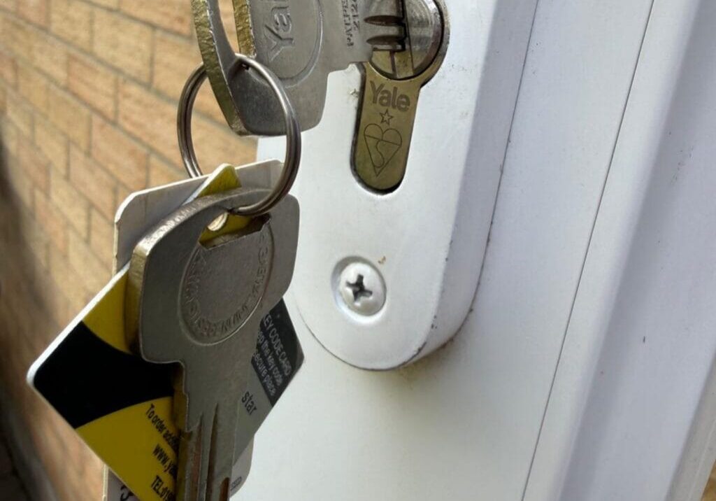 Close-up photograph showing keys inserted into a high security lock on a white patio door in Colchester.