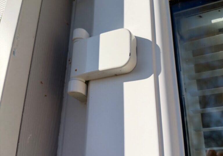 Close-up view of the top hinge of a white uPVC French door showing hinge mechanism and part of the door frame in Gosfield.