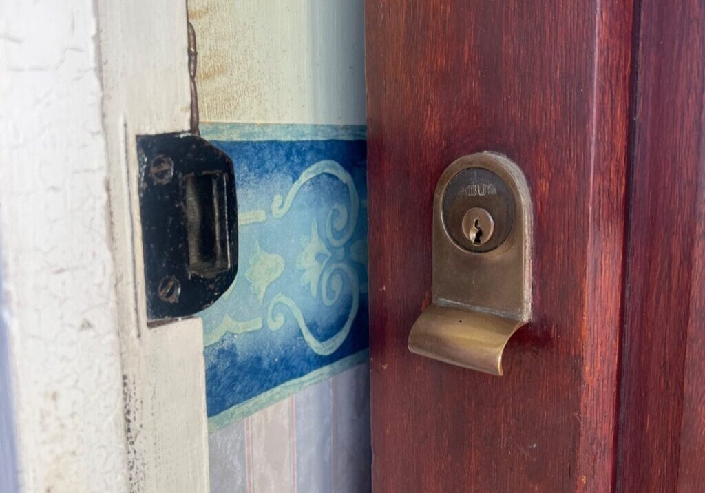 Close-up image showing the lock cylinder and strike plate fitted on a wooden front door and door frame in Maldon